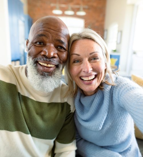 happy-senior-diverse-couple-in-living-room-sitting-on-sofa-making-video-call.jpg